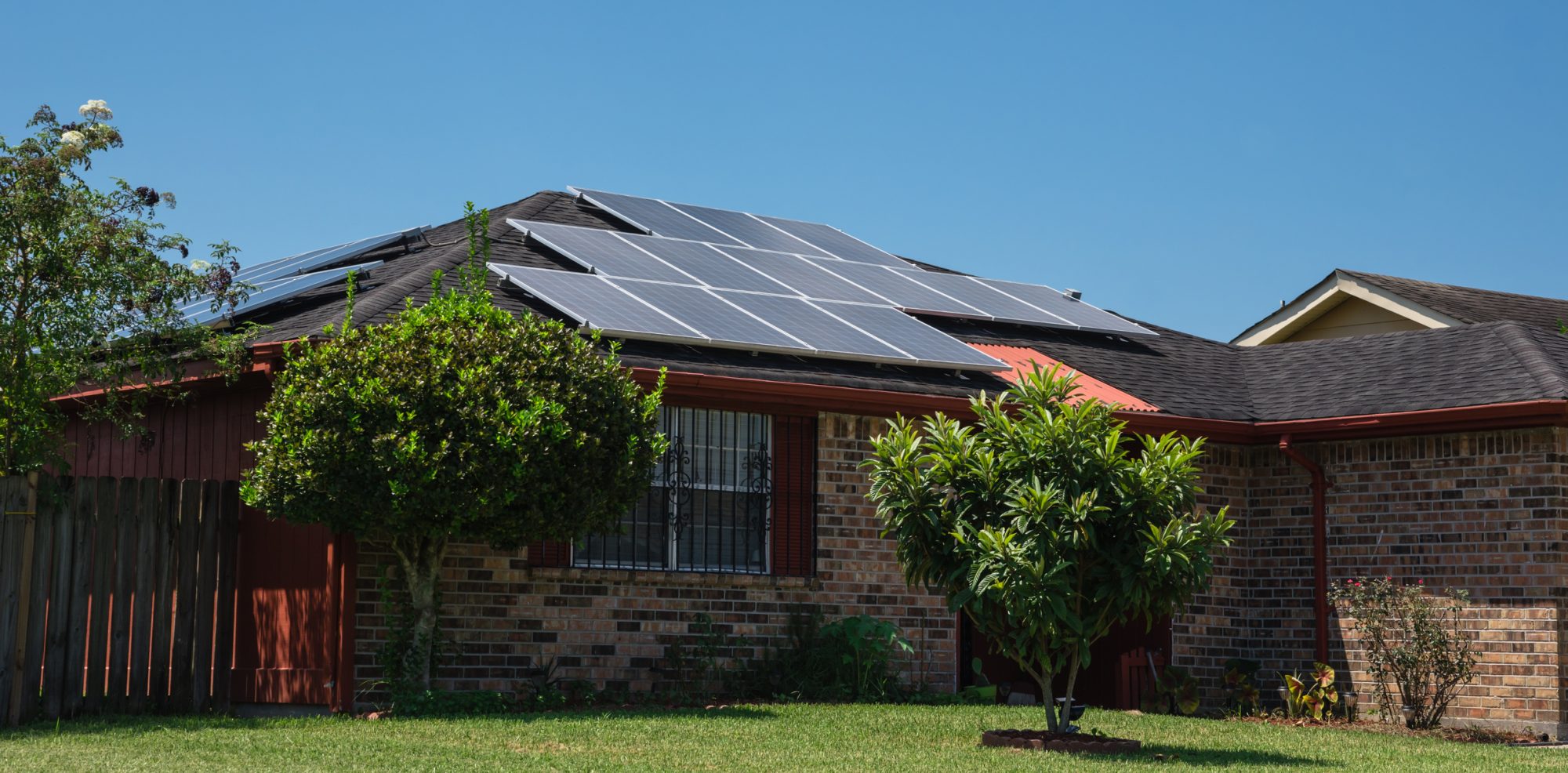 Close-up solar panels on the gable roof suburban house blue sky. Photovoltaic solar collector for renewable clean green energy, East of Louisiana, USA. Sustainable, efficient concept. Panorama style